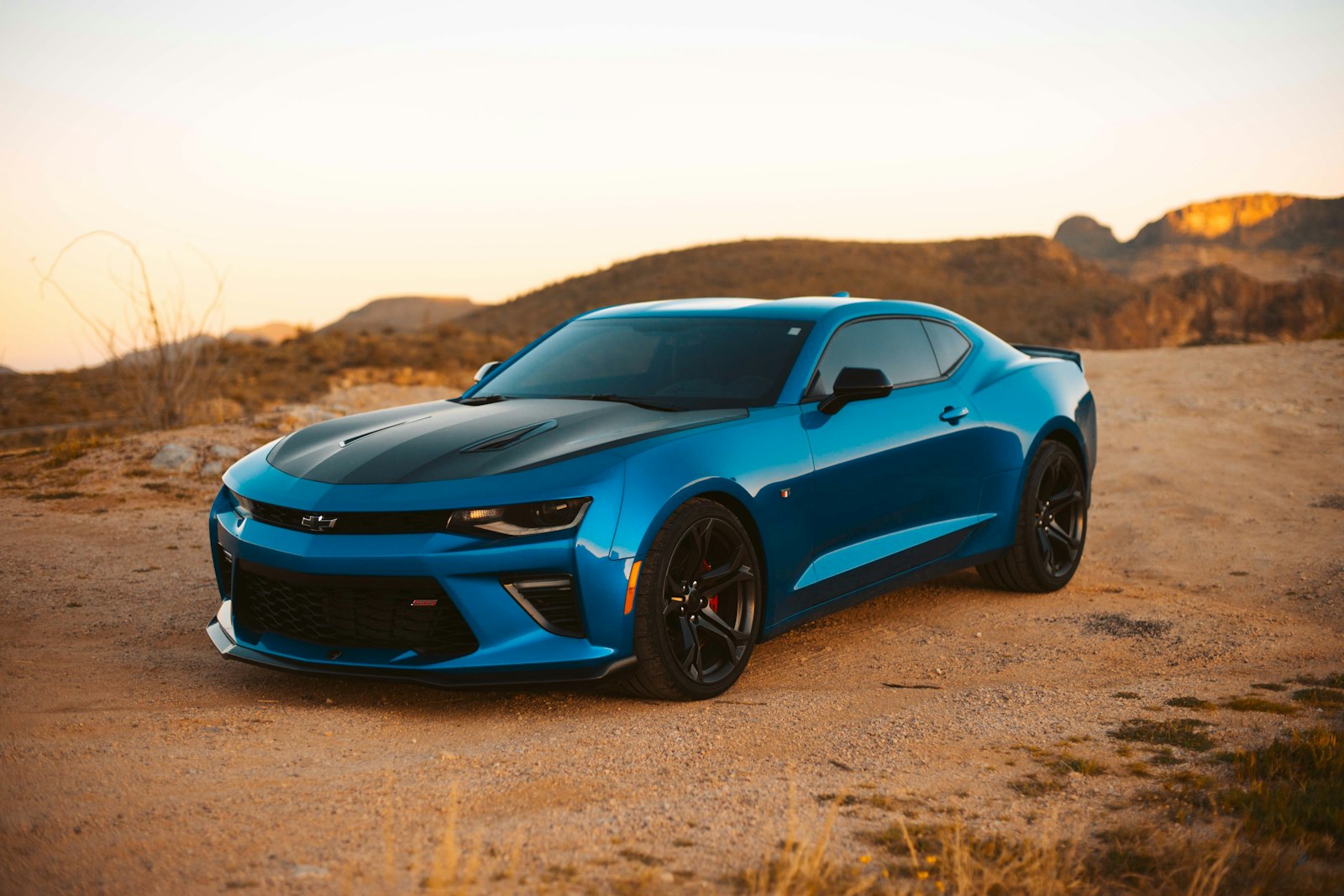 Blue coupe in desert hills at dusk